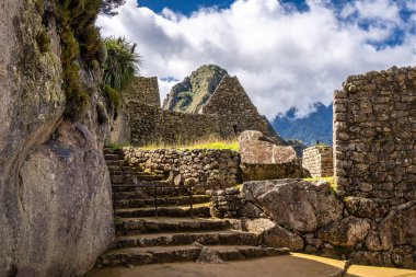 Çimenli yeşil teraslar ve Machu Picchu 'nun içinde parlak And gökyüzünün altında oyulmuş taş duvarlar.