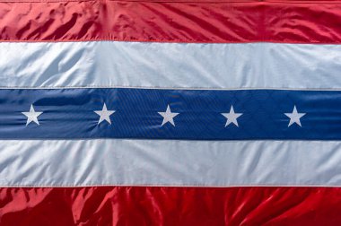 Kırmızı, beyaz ve mavi çizgili vatansever bir bayrak. Merkezi mavi bölümde Amerikan gurur ve geleneğini sembolize eden beyaz yıldızlar yer almaktadır. ABD