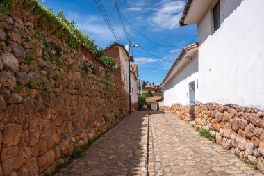 Peru, Chinchero 'da beyaz kerpiç evleri ve taş duvarlarla kaplı sessiz bir cadde. Parke taşı yolu, şehrin sömürge ve And mirasını yansıtıyor.
