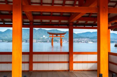 Kutsal Itsukushima Tapınağı yüzen kırmızı torii kapısıyla Japonya 'daki Miyajima adasının sakin sularına ve dağlarına bakıyor.