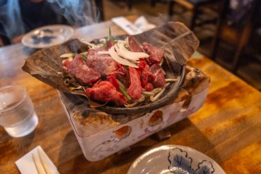 Japonya 'nın Takayama kentindeki geleneksel bir restoranda manolya yaprağında pişen çiğ Hida Wagyu et dilimleri.