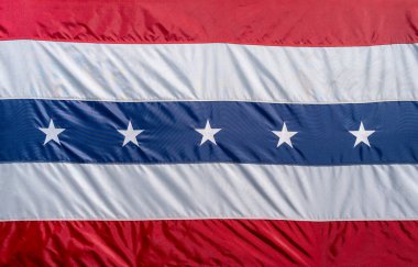 Kırmızı, beyaz ve mavi çizgili vatansever bir bayrak. Merkezi mavi bölümde Amerikan gurur ve geleneğini sembolize eden beyaz yıldızlar yer almaktadır. ABD