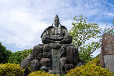 Şogun Minamoto no Yoritomo 'nun bronz heykeli yeşil ve gökyüzü ile çevrili Genjiyama Park, Kamakura' daki taş bir üste zırh içinde oturuyordu.