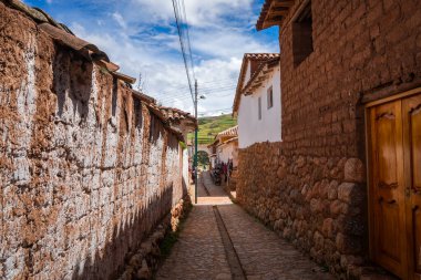 Peru, Chinchero 'da beyaz kerpiç evleri ve taş duvarlarla kaplı sessiz bir cadde. Parke taşı yolu şehirleri yansıtıyor. Sömürge ve And mirası.