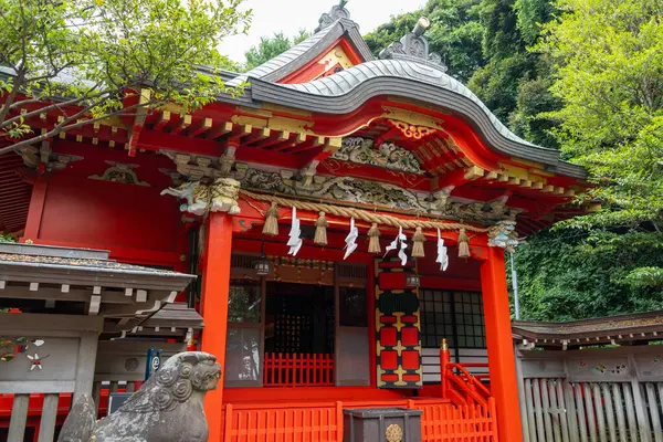 Enoshima-Shrine Nakatsunomiya 'nın parlak kırmızı ana salonu Japonya' nın Enoshima Adası 'ndaki ağaçlar, geleneksel fenerler ve koruyucu heykellerle çevrilidir.