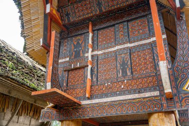 Geometrik desenler ve sembolik motifler geleneksel bir Toraja evinin ahşap panellerini süsler, Sulawesi halkının kültür ve inançlarını yansıtır.