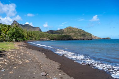 Hakaui Körfezi, Nuku Hiva, Marquesas Adaları, Fransız Polinezyası 'nda tenha bir kumsal. Yükselen kayalıklar, yemyeşil bitki örtüsü ve sallanan palmiye ağaçları çarpıcı bir tropik cennet yaratır.