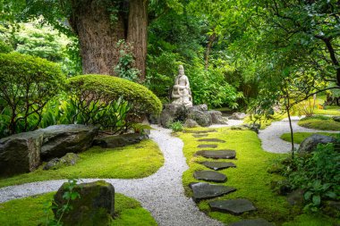Kannon 'un sakin heykeli, Kamakura' daki Hokoku-ji türbesindeki ağaçlar ve taşlarla çevrili yosun kaplı zen bahçesinde duruyor.