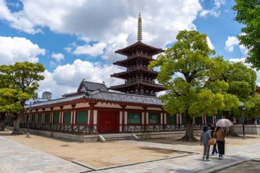 İki kadın, Osaka 'daki Shitenno ji Tapınağı' nın beş katlı tapınağının yakınındaki ağaçların altında şemsiyeyle dolaşıyorlar.