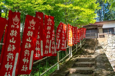 Hareketli kırmızı bayraklar Japonya 'nın Takayama kentindeki yemyeşil ormandaki Nishikiyama Tapınağı' nın taş basamaklarını sarıyor.