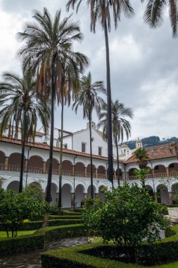 Quito, Ekvador 'daki tarihi San Francisco manastırı ve kilise avlusunda koloni mimarisi, palmiye ağaçları ve sakin bir çeşme yer alıyor.
