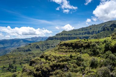 Peru 'daki Waqrapukara bölgesinde dramatik kaya oluşumları, yeşil vadiler ve dik uçurumlar yer almakta, And dağlarının parlak mavi gökyüzü altında nefes kesen manzaraları sunmaktadır.