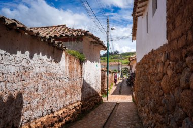 Peru, Chinchero 'da beyaz kerpiç evleri ve taş duvarlarla kaplı sessiz bir cadde. Parke taşı yolu, şehrin sömürge ve And mirasını yansıtıyor.