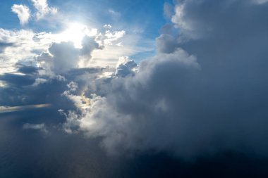 Güneş tarafından aydınlatılan görkemli bulutlar yukarıdan görülen dramatik bir gökyüzü yaratır. Parlak güneş ışığı, derin mavi gökyüzü ve gölgeli bulutlarla çelişiyor.