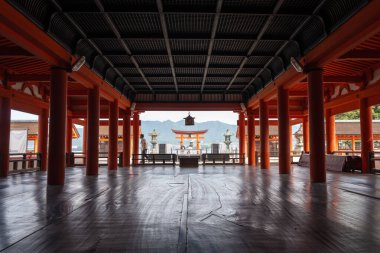 Kutsal Itsukushima Tapınağı yüzen kırmızı torii kapısıyla Japonya 'daki Miyajima adasının sakin sularına ve dağlarına bakıyor.
