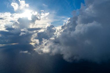 Güneş tarafından aydınlatılan görkemli bulutlar yukarıdan görülen dramatik bir gökyüzü yaratır. Parlak güneş ışığı, derin mavi gökyüzü ve gölgeli bulutlarla çelişiyor.