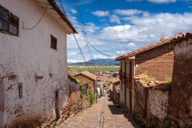Peru, Chinchero 'da beyaz kerpiç evleri ve taş duvarlarla kaplı sessiz bir cadde. Parke taşı yolu, şehrin sömürge ve And mirasını yansıtıyor.