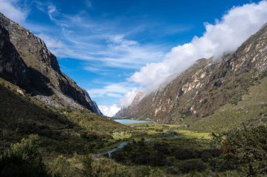 Yükselen dağlar arasında yemyeşil bir vadi uzanır, sakin bir göle uzanan dolambaçlı bir nehir. Bu nefes kesici manzara, Peru, Huaraz 'daki Laguna 69 yürüyüşünün bir parçası.