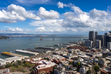 Modern gökdelenlerle San Francisco şehir merkezinin hava manzarası ve dağınık bulutlu mavi gökyüzünün altındaki Bay Bridge.