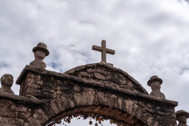 Taquile Adası, Titicaca Gölü, Peru 'daki geleneksel bir köye bir haç ve oyma figürlü taş kemer ile giriş yapılır. Yapı kurumuş çiçekler ve yerel süslemelerle süslenmiş.