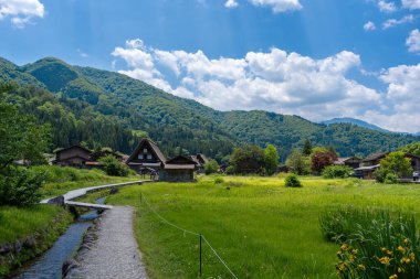 Japon yeşil dağlarındaki Shirakawa-go köyünün huzur dolu atmosferini, şatafatlı evler, canlı ağaçlar ve yemyeşil otlaklar karakterize eder.