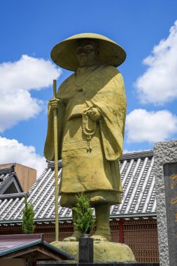 Keşiş Shinran heykeli Osaka 'daki Shitenno-ji Tapınağı' nda dimdik duruyor. Elinde dua boncukları ve açık mavi gökyüzünün altında yürüyen bir asa var.