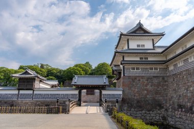 Japonya 'da yeşil ve mavi gökyüzüyle çevrili, taş duvarları ve hendeği olan Kanazawa Kalesi' nin geleneksel Japon mimarisi.