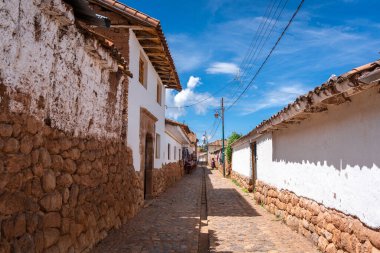 Peru, Chinchero 'da beyaz kerpiç evleri ve taş duvarlarla kaplı sessiz bir cadde. Parke taşı yolu, şehrin sömürge ve And mirasını yansıtıyor.