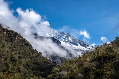 Engebeli arazisi, altın çayırları ve kısmen dramatik bulutlarla kaplı karlı tepeleri olan çarpıcı bir And Vadisi. Bu nefes kesici sahne, Huaraz, Peru 'daki Laguna 69 yürüyüşünün bir parçası.