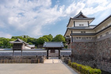 Japonya 'da yeşil ve mavi gökyüzüyle çevrili, taş duvarları ve hendeği olan Kanazawa Kalesi' nin geleneksel Japon mimarisi.