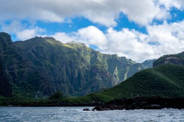 Yüksek yeşil kayalıklar Hakaui Körfezi, Nuku Hiva, Marquesas Adaları, Fransız Polinezyası 'na hakim. Bereketli bitki örtüsü, palmiye ağaçları ve derin vadiler uzak Pasifik kıyı şeridi boyunca nefes kesici bir doğal manzara yaratır.