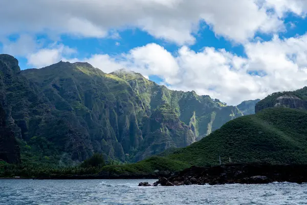Yüksek yeşil kayalıklar Hakaui Körfezi, Nuku Hiva, Marquesas Adaları, Fransız Polinezyası 'na hakim. Bereketli bitki örtüsü, palmiye ağaçları ve derin vadiler uzak Pasifik kıyı şeridi boyunca nefes kesici bir doğal manzara yaratır.