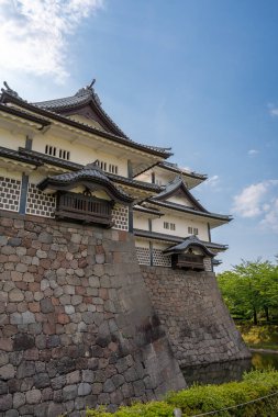 Japonya 'da yeşil ve mavi gökyüzüyle çevrili, taş duvarları ve hendeği olan Kanazawa Kalesi' nin geleneksel Japon mimarisi.