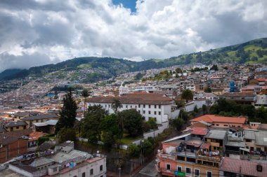 Quito, Ekvador 'un panoramik manzarası. Şehir vadiye yayılmış ve arka planda yeşil tepeler var.