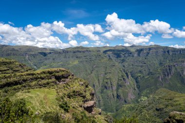 Peru 'daki Waqrapukara bölgesinde dramatik kaya oluşumları, yeşil vadiler ve dik uçurumlar yer almakta, And dağlarının parlak mavi gökyüzü altında nefes kesen manzaraları sunmaktadır.