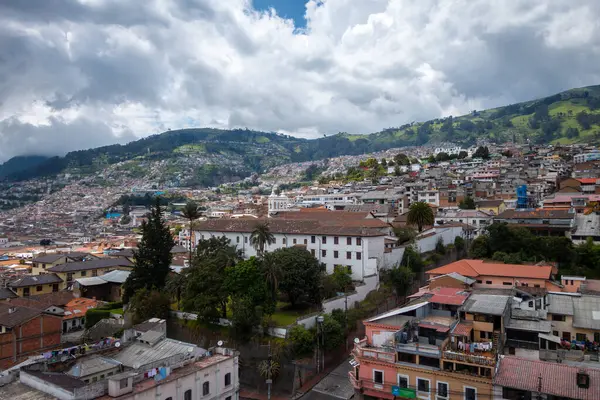 Quito, Ekvador 'un panoramik manzarası. Şehir vadiye yayılmış ve arka planda yeşil tepeler var.