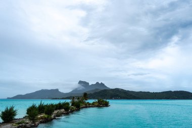 Palmiye ağaçlarıyla kaplı bir sahilden Bora Bora adasının manzarası Fransız Polinezyası 'nda mükemmel bir tropik cennet sunuyor.