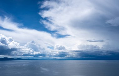 Peru, Amantani Adası 'ndan Titicaca Gölü' nün engin manzarası. Gökyüzünde hareket eden kara fırtına bulutları sakin suların üzerine gölgeler düşürüyor.