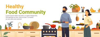 Sağlıklı gıda topluluğu mutfakta yemek pişiriyor. Modern mutfak sahnesinde iki kişi taze sebze, meyve ve çatal bıçak örnekleriyle çevrili yiyecekleri hazırlıyor.