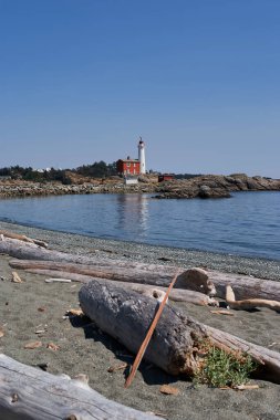Kırmızı binası ve beyaz kulesi ile kayalık bir noktada duran Fisgard Deniz fenerinin manzarası Victoria, Vancouver Adası, Kanada yakınlarındaki sakin sulara yansıyor..