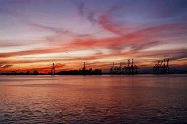Sakin suları ve renkli gökyüzü ile Vancouver feribot limanı üzerinde canlı bir günbatımı manzarası.