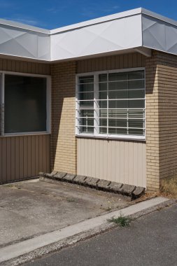 Umut, İngiliz Kolombiyası, Kanada 'da güneş ışığı altında parmaklıklı penceresi ve beton zemini olan bej bir tuğla duvar..