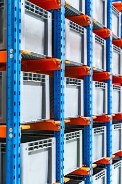 Otomatik deponun hücrelerindeki plastik kutular. Metal inşaat deposu rafları