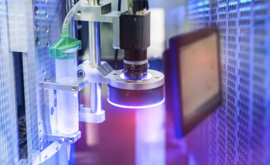 Robot elinde tutkal şırıngası. Cep telefonu fabrikasında robotik makine görme sistemi var.