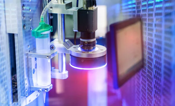 Robot elinde tutkal şırıngası. Cep telefonu fabrikasında robotik makine görme sistemi var.