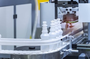 Otomatik sıvı dolum makinesinin taşıyıcı bandında polipropilen beyaz şişeler taşınıyor