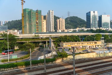 SHENZHEN, ÇİN - 12, 2024: Shenzhen Metro Treni, SHENZHEN 'deki siluet arkaplanlı tren raylarında çalışan istasyona yaklaşıyor.