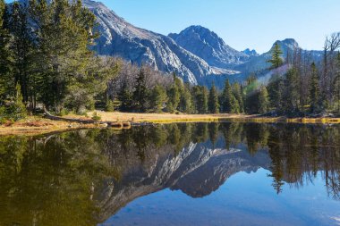Sakin sulardaki kayaların yansımasıyla dağdaki gölün sakin manzarası..