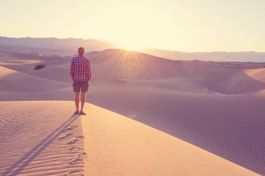 Çöldeki kum tepelerinin arasında bir yürüyüşçü