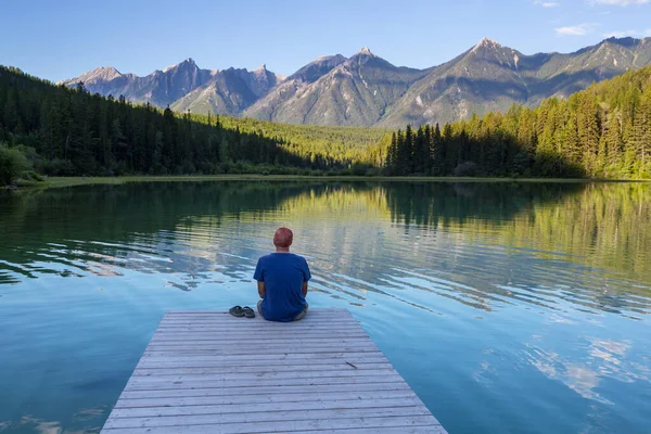 穏やかな湖のそばで男が寛いでいる リラクゼーション休暇 — ストック写真